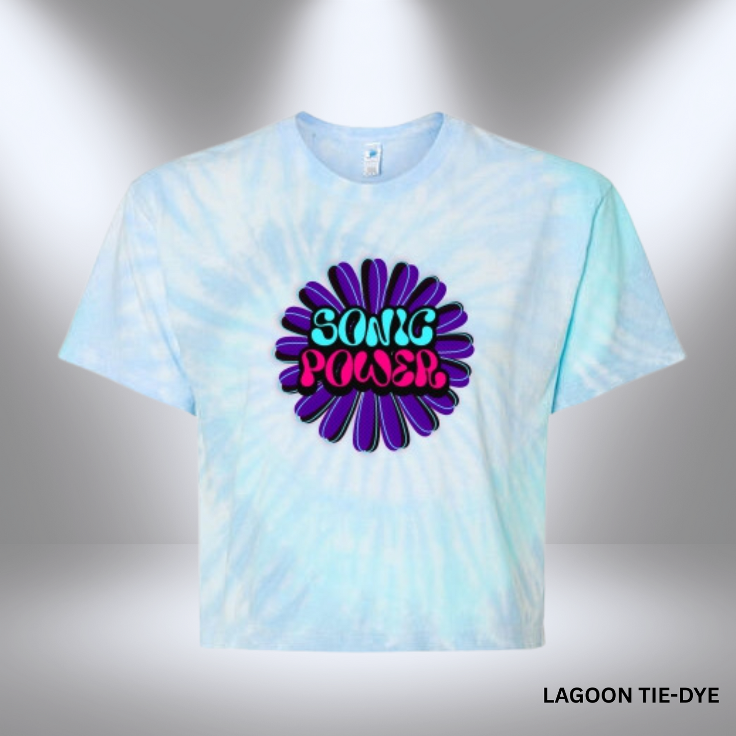 A vibrant, flower-shaped graphic with the words "Sonic Power" in retro bubble letters, filled with teal and hot pink, on a tie-dye blue cropped shirt.