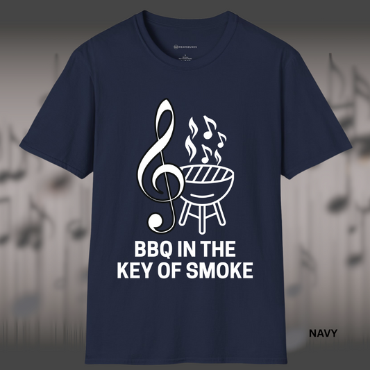 Design featuring a large white treble clef beside a charcoal grill emitting smoke shaped like music notes, with bold text below reading “BBQ IN THE KEY OF SMOKE.”