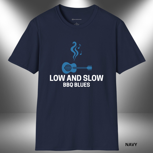 Stylized graphic of a blue acoustic guitar with grill grates over the sound hole, rising smoke shaped like music notes above it. The text “LOW AND SLOW BBQ BLUES” appears below in bold white lettering on a black background.